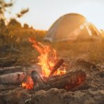 a campfire with a tent in the distance