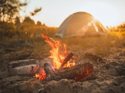 a campfire with a tent in the distance