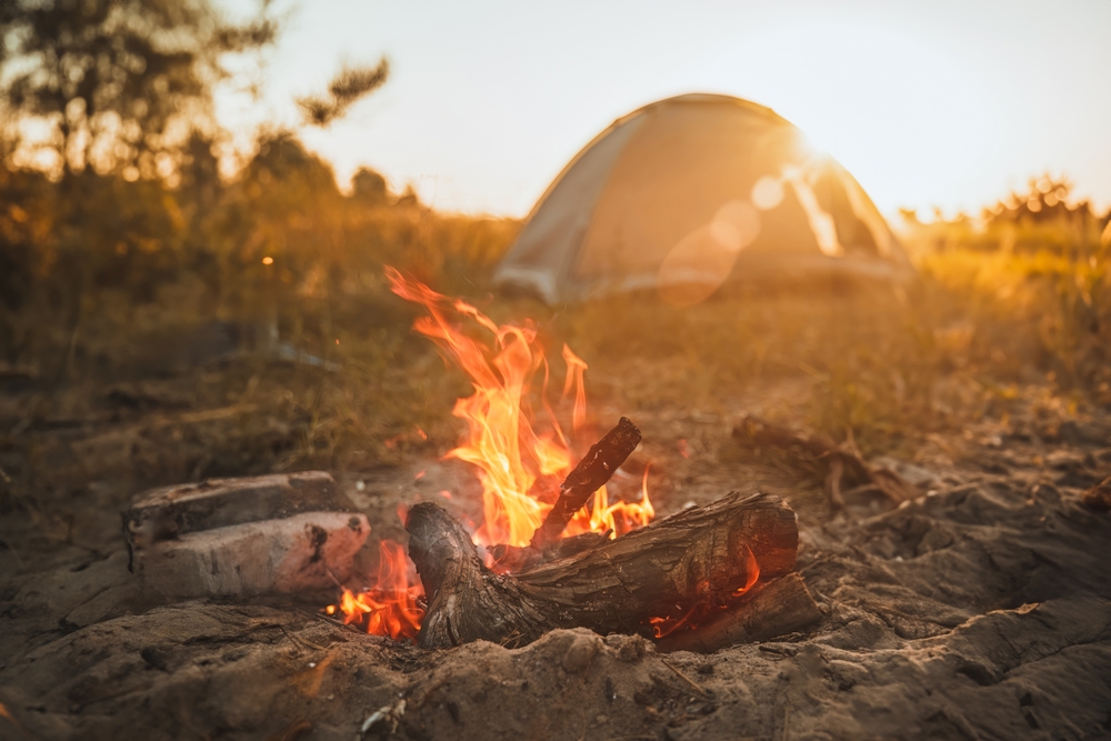 a campfire with a tent in the distance