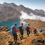 A group of hikers using trekking poles as they descend a mountain