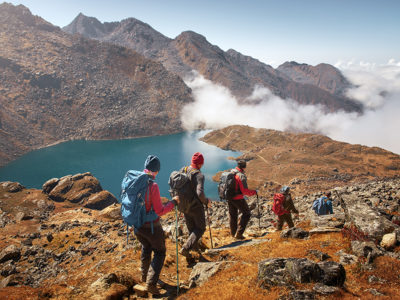 A group of hikers using trekking poles as they descend a mountain