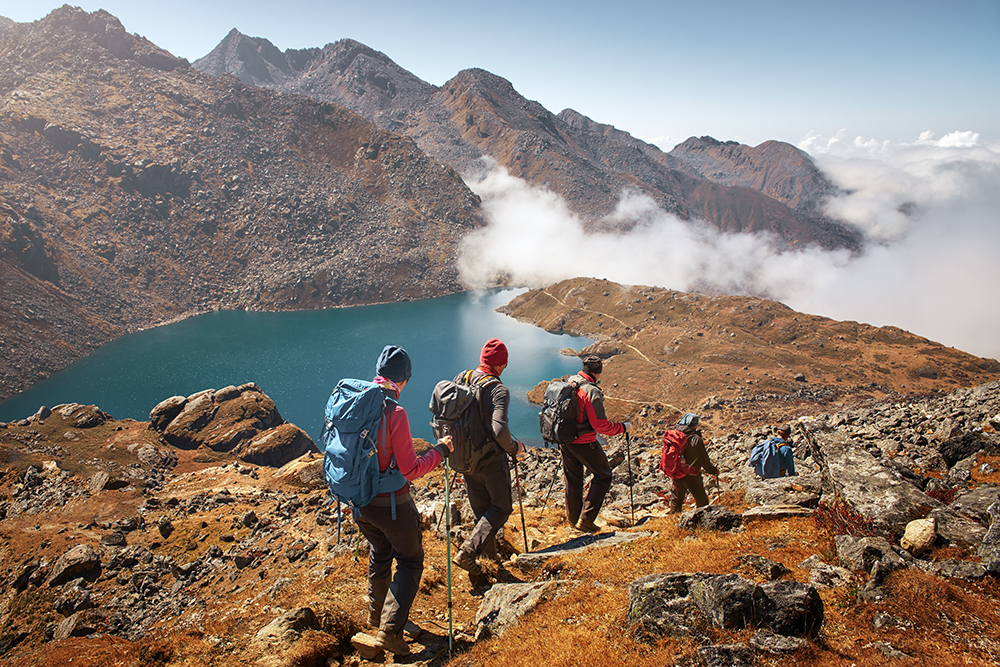 A group of hikers using trekking poles as they descend a mountain