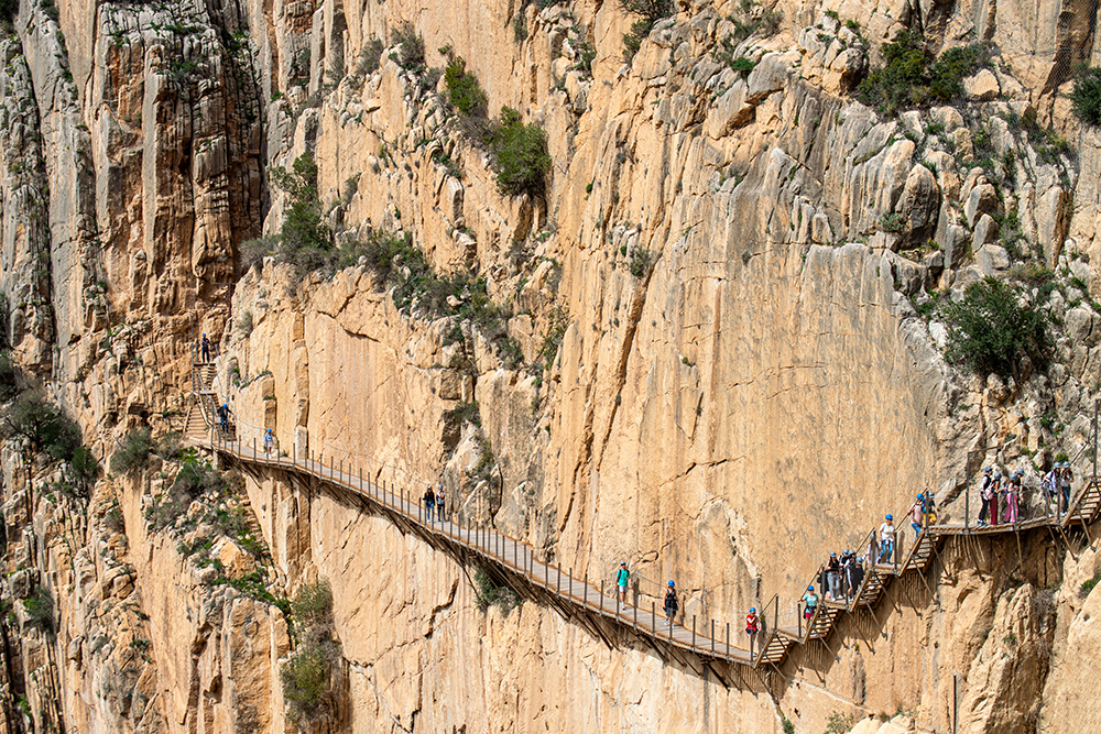 Hikers traverse a cliff hiking trail in Malaga