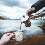 a man pours coffee into an enamel mug held by a woman