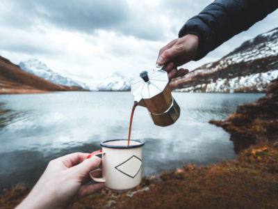 a man pours coffee into an enamel mug held by a woman