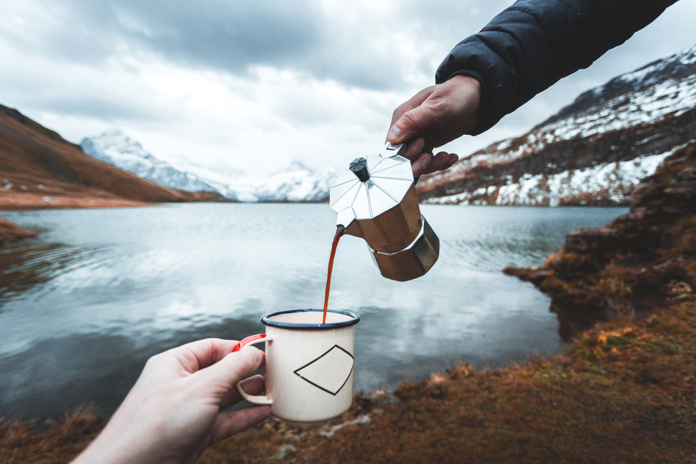 a man pours coffee into an enamel mug held by a woman