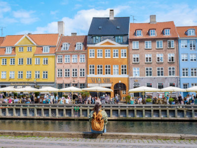 a woman sits beside a canal in Copenhagen