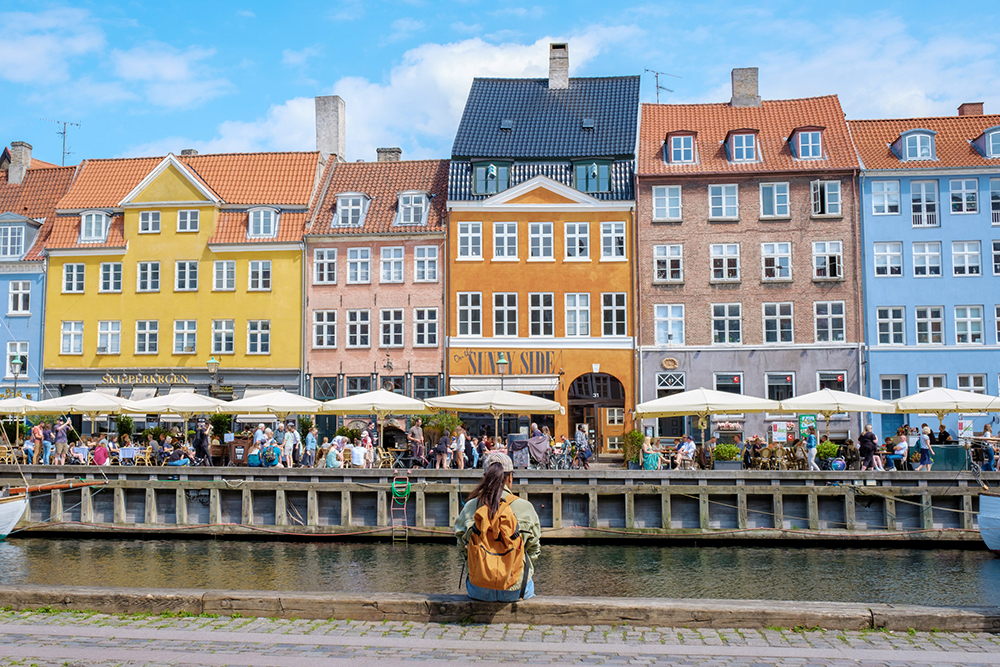 a woman sits beside a canal in Copenhagen