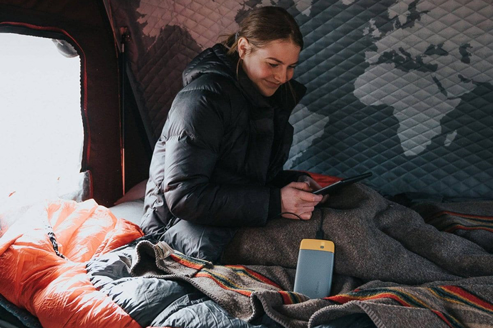 woman in a tent using the best power banks for camping and hiking